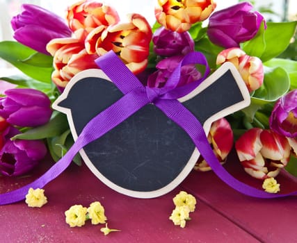 Fresh colorful tulips and small chalkboard with text space