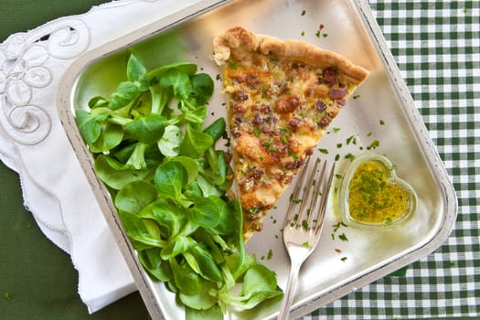 Square plate with quiche Lorraine and lamb's lettuce