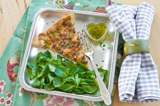 Square plate with quiche Lorraine and lamb's lettuce