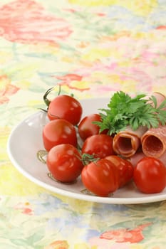 Detail of a breakfast table with tomatoes and cold cuts,arranged on a plate
