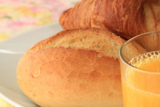 Detail of a breakfast table with rolls,croissant and orange juice