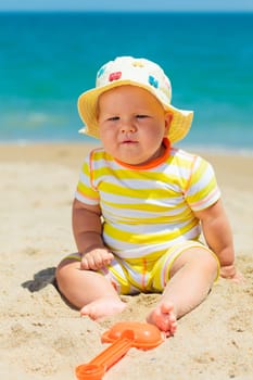 Cute baby on the tropical beach playing toys