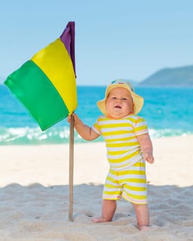 Cute baby on the tropical beach with flag