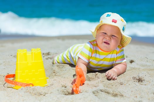 Cute baby on the tropical beach playing toys