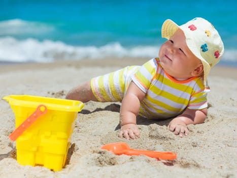 Cute baby on the tropical beach playing toys