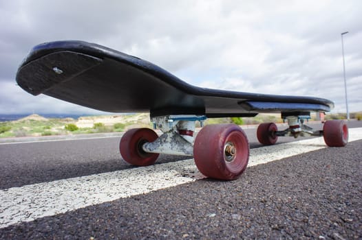 Vintage Style Longboard Black Skateboard on an Empty Asphalt Desert Road