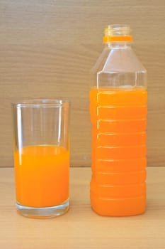 Orange juice in plastic bottle and glass on table