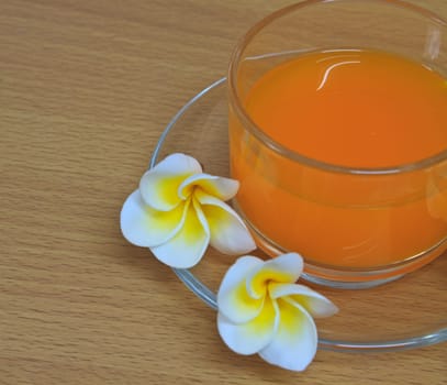 Close up orange juice with flowers on wooden table