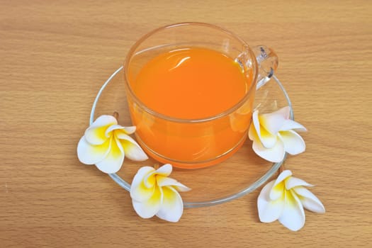 Close up orange juice with flowers on wooden table
