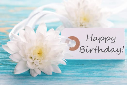 Label with Happy Birthday on wooden turquiose Background with white Flowers