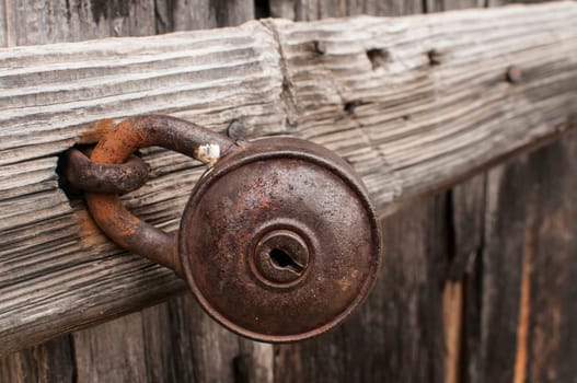 Old rusty padlock on weathered wooden door closeup