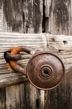 Old rusty padlock on weathered wooden door closeup