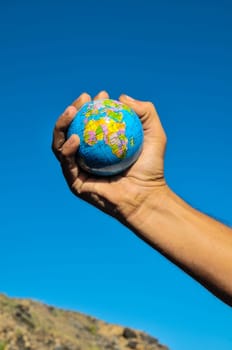 Vintage Old Globe Earth and Human Hand over a Blue Sky