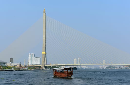 A traditional wooden boat at the Bruecke Saphan Phra Ram Vlll on the Mae Nam Chao Phraya River in the capital Bangkok of Thailand in South East Asia.