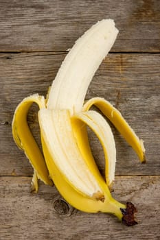 Peeled fresh banana on the wood background