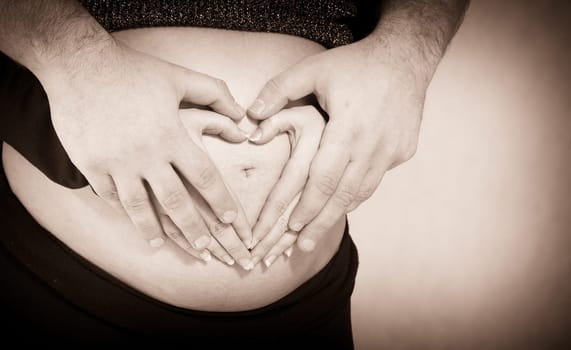Couple Forming Heart Shape on Pregnant Belly
