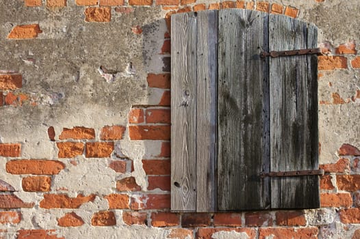 The close-up of a wooden hatch in the brick wall of a barn.