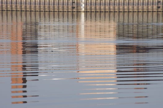 The photograph of water reflections on a dam wall.