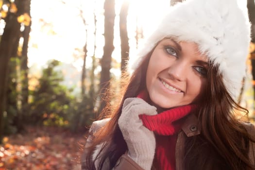 Happy brunette is having a nice time in the park while it's autumn