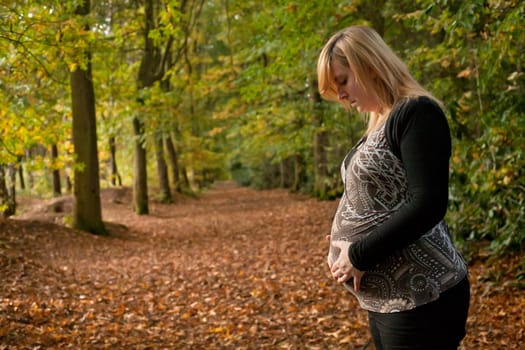 Blond young girl is waiting for her little child. Shoot in the forest