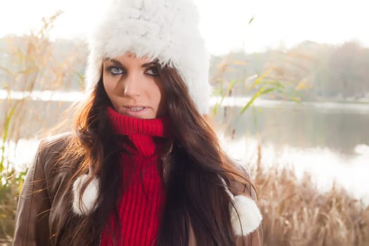 Happy brunette is having a nice time in the park while it's autumn