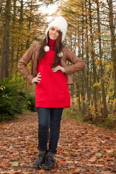 Happy brunette is having a nice time in the park while it's autumn
