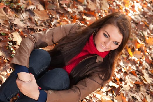 Happy brunette is having a nice time in the park while it's autumn
