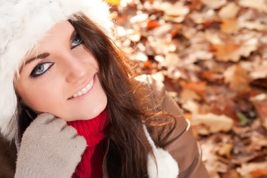 Happy brunette is having a nice time in the park while it's autumn