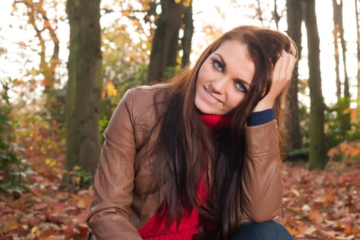 Happy brunette is having a nice time in the park while it's autumn