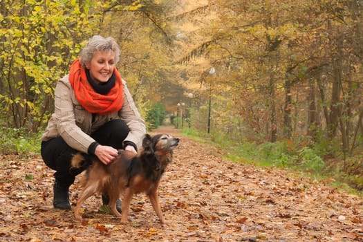 Middle aged woman in the autumn forest with her dog