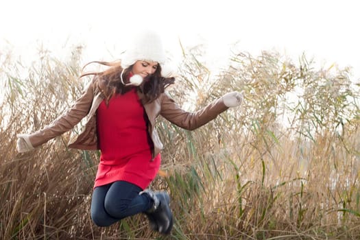 Happy brunette is having a nice time in the park while it's autumn