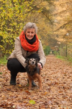 Middle aged woman in the autumn forest with her dog
