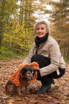 Middle aged woman in the autumn forest with her dog