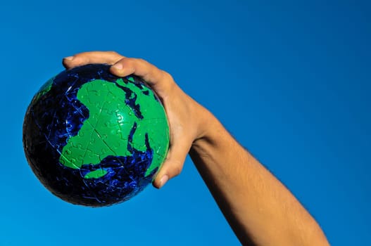 Vintage Old Globe Earth and Human Hand over a Blue Sky