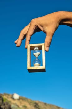 Time Concept White Sand Hourglass on the Volcanic Rocks