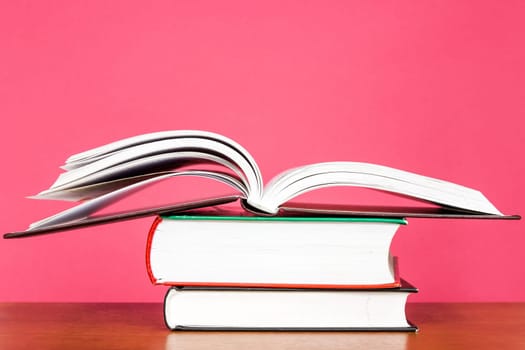 Education concept. Pile of books on pink background