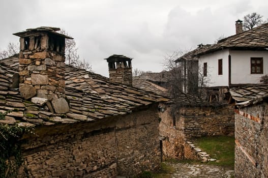 Old stone tiles slide-roof and stonewall rural houses in mountain village