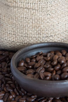 Coffee beans in a small clay pot. Image has a background of jute fibers