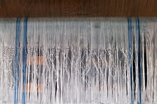 The photograph of parallel fabric threads in a loom.