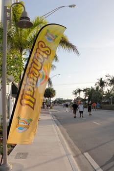 WILTON MANORS, FLORIDA - JUNE 22, 2013: Yellow flag banner with Stonewall and summer pride name, rainbows, graphics at the gay pride celebration in Wilton Manors, Florida with people on Wilton Drive.