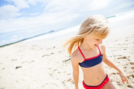 Smiling cute young girl having fun at beach on sunny day