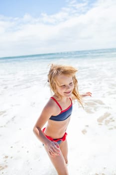 Smiling cute young girl having fun at beach on sunny day