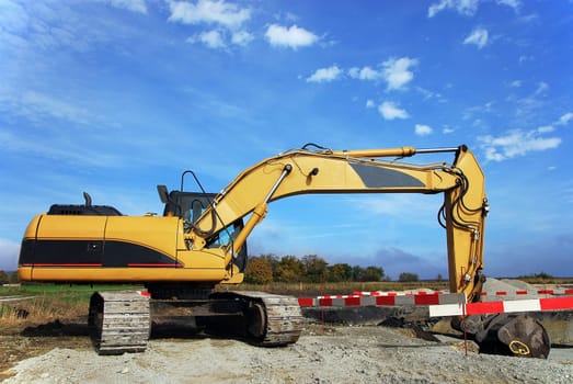 Excavator on construction site digs a hole