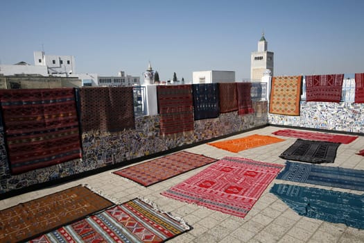A roof terrace with carpets and the Zaytouna Mosque or Grand Mosque in Souq or Bazzar in the Old Town of Tunis on the Mediterranean Sea in Tunisia in North Africa.