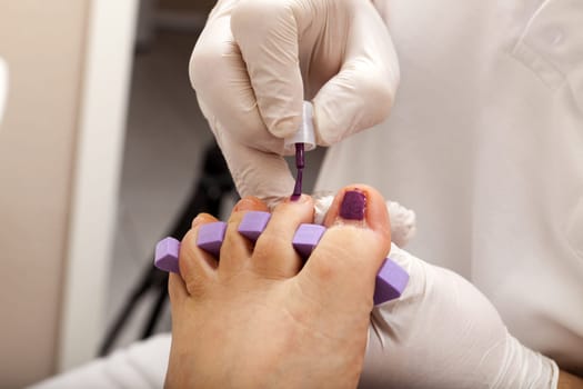 Foot care worker paints a customer's toe nails
