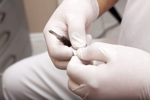 Foot care worker opens pack with scalpel blade