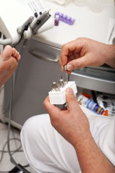 Foot care worker takes polishing attachment out of a box