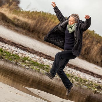 happy active older woman pensioner senior in the open at the sea in autumn