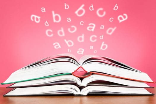 Open books with glowing letters flying out over a pink background