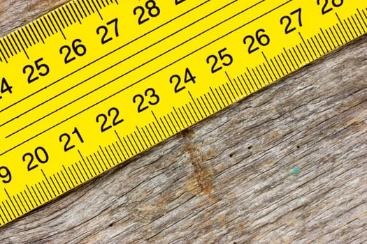 Close-up yellow ruler on a wooden background